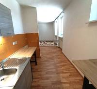 A kitchen in a 2-room apartment with a wooden decor floor and orange tiles.