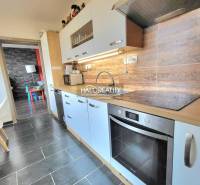 A kitchen in a 3-room apartment with light cabinets and a wood-patterned floor.