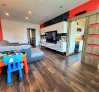 Living room in a three-room apartment with a wooden-patterned floor and colorful children's furniture.