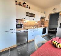 A kitchen in a 3-room apartment with a wooden decor floor and appliances.