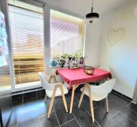 Dining area in a 3-room apartment with a tiled floor and large windows.