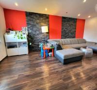 Living room in a 3-room apartment with a comfortable sofa and a wooden-patterned floor.