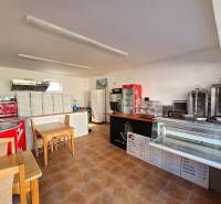 Interior of a gastro space with a counter, refrigerated display cases, and a stack of pizza boxes.