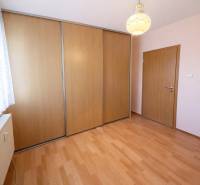 A room in a 2-room apartment with a built-in wardrobe and a floor with a wooden decor.
