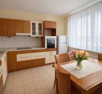 A kitchen in a 2-room apartment with flowers on the table and built-in appliances.