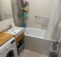 Bathroom with a shower bath and washing machine in a 4-room apartment with elegant tiles.