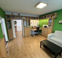 Living room in a 4-room apartment, with a wooden decor floor and a bookshelf.