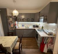 A kitchen in a 4-room apartment with a wooden decor floor and a corner kitchen unit.