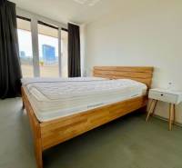 A bedroom with a wooden bed, a nightstand, and a balcony in a 3-room apartment.
