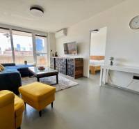 Living room of a three-room apartment with a sofa, television, and balcony.