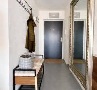 The hallway of a 3-room apartment with a bench, a coat rack, and a large mirror on the wall.