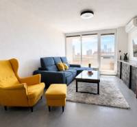 Living room in a 3-room apartment with a yellow armchair, a blue sofa, and a TV on the wall.