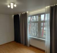 A room with a large window, blackout curtains, and a floor with a wooden decor. Commercial spaces.