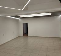 Commercial space with white walls and tiles, ceiling with strip lighting.