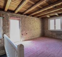 The interior of a family house with bare brick walls, a wooden ceiling, and floor.