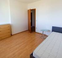 A room in a 3-room apartment, with a bed, a dresser, and a floor with a wooden decor.
