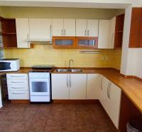 A kitchen in a 3-room apartment with a combination of white furniture and a wooden decor floor.