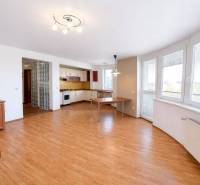 Spacious living area with kitchen and wood-patterned flooring in a 3-room apartment.