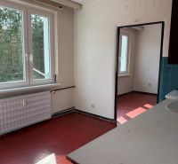 A kitchen in a 2-room apartment with a red floor and a large window.