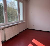 A room with a red floor in a 2-room apartment, a large window lets in natural light.