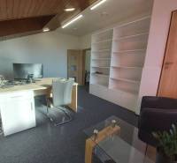 Offices with white shelves, wooden ceiling, desk, and conference table.