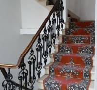 A staircase with wrought iron railing and a colorful carpet in the offices.
