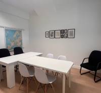 An office with white furniture, a map of Europe on the wall, and a floor with a wooden decor.