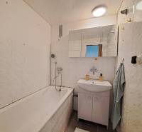 Bathroom in a 2-room apartment with a bathtub, sink, and mirror.