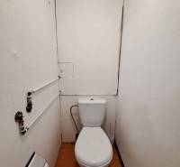 A bathroom with a toilet and a wooden decor floor in a 2-room apartment.