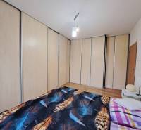 A bedroom with a large built-in wardrobe and a bed in a 2-room apartment.