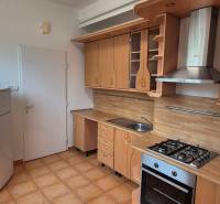 A kitchen in a 3-room apartment with a wooden decor kitchen unit and appliances.