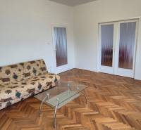 Living room in a 3-room apartment with a sofa and a glass table, floor with wood decor.