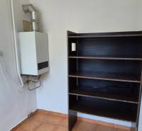 Boiler and shelf in the space of a 3-room apartment, with tiles on the floor.