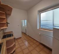 A kitchen in a 3-room apartment with tiles and a large window, light walls, wooden shelves.