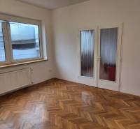 A room in a 3-room apartment with white walls and a wooden decor floor.