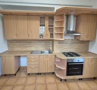 A kitchen with light wooden cabinets and appliances in a three-room apartment.