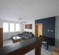Living room in a three-room apartment with a corner sofa and a floor with a wooden decor.