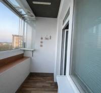 Glazed loggia in a 3-room apartment with a wooden decor floor.