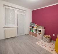 A children's room in a three-room apartment with a wooden decor floor and colorful walls.