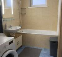 A bathroom with a bathtub, sink, and washing machine in a 3-room apartment, blue tiles.