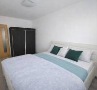 A bedroom with a bed, built-in wardrobe, and wooden decor flooring in a 3-room apartment.