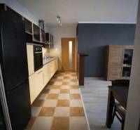 A kitchen in a 3-room apartment with a kitchen unit and a dining table, tiled floor.