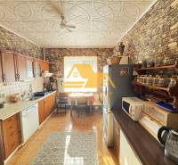 A kitchen in a family house with a wooden decor floor and stone walls.