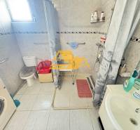 Bathroom in a family house with a washing machine, shower, and toilet.