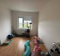 A room in a family house with a wooden decor floor and a view of the garden.