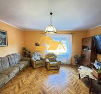 Living room in a family house with wood-patterned flooring, comfortable seating, and a painting.