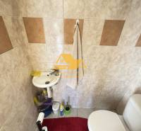 Bathroom with a sink and toilet, tiles combine light and brown shades.