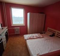 A bedroom with a bed and a wardrobe in a 3-room apartment, red walls.
