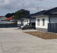 Family houses on Leknová Street in Láb with adjacent parking spaces and a fence.