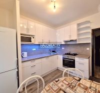 A kitchen in a 4-room apartment with a wood-patterned floor and white cabinets.